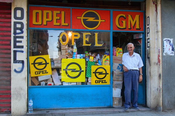 Old man is standing at a shop entrance