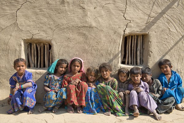 Children sitting in front of a mudbrick house