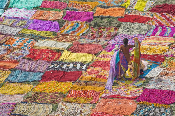 Colourful saris are laid out on the sand for drying after washing