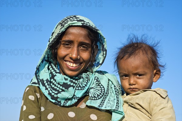 Indian woman with headscarf holding a little boy in her arms