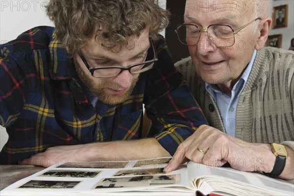 Grandson and grandfather looking at photos in a photo album