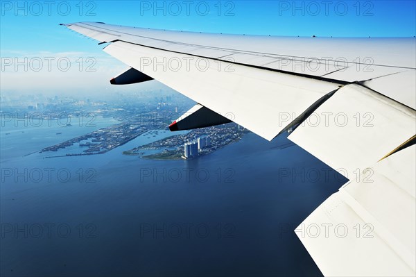 Wing of a plane and views of the port area of ??Jakarta on landing approach