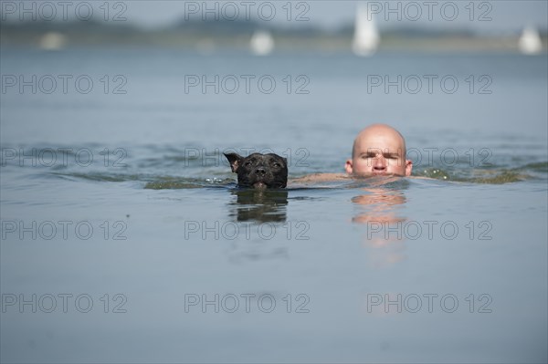 A man and a dog swimming in a lake