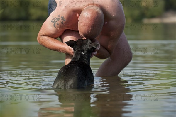 Man standing in the water kissing his dog