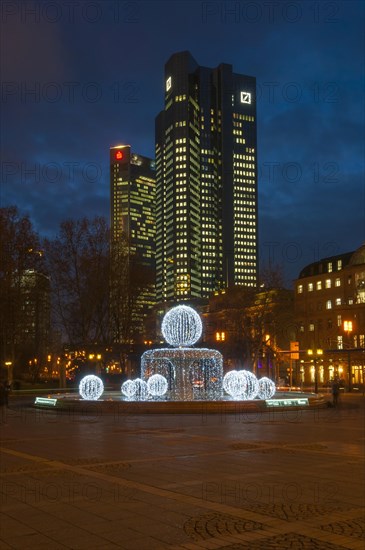 Illuminated Lucae Fountain on Opernplatz square in front of Trianon high-rise building and the Deutsche Bank Twin Towers