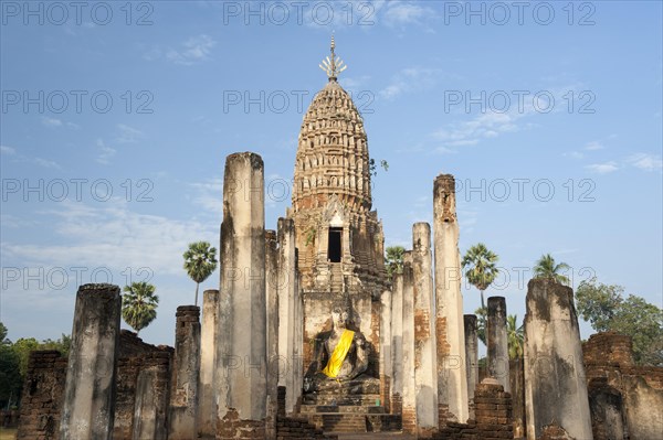 Seated Buddha statue in front of a chedi