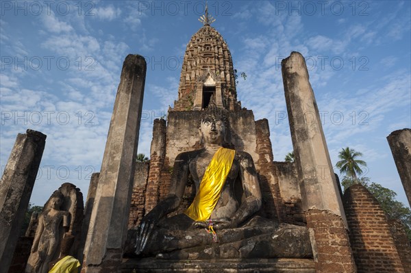 Seated Buddha statue in front of a chedi