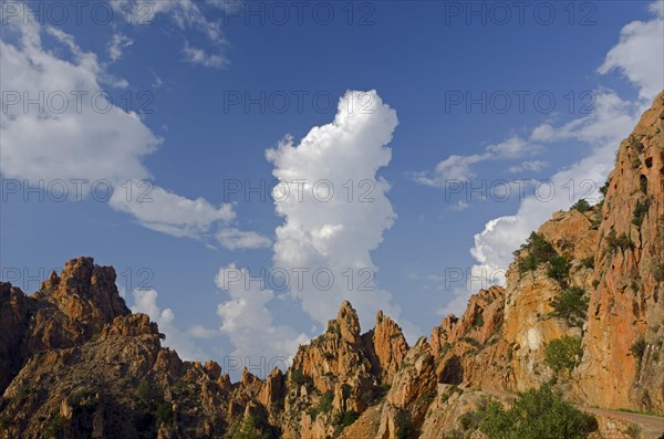 The typical bizarre red rocks of the Calanche of Piana below a blue sky and some clouds. The Calanche of Piana is in the western part of the island Corsica