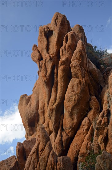 The typical bizarre red rocks of the Calanche of Piana below a blue sky and some clouds. The Calanche of Piana is in the western part of the island Corsica