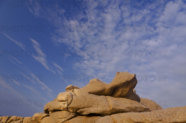 Bizarre granite rocks at the coast of the mediterranean sea in Calvi below a blue sky with some clouds. Calvi is in the department Haute-Corse