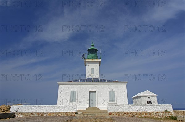 The white lighthouse on the island Ile de la Pietra near L'Île-Rousse below a blue sky with some clouds. L'Île-Rousse  is in the department Haute-Corse