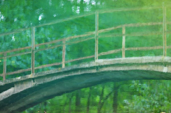 Reflection of a bridge leading across a small stream