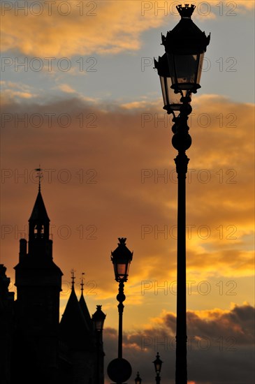 The Conciergerie and the typical Parisian street lights against dramatic clouds in the evening