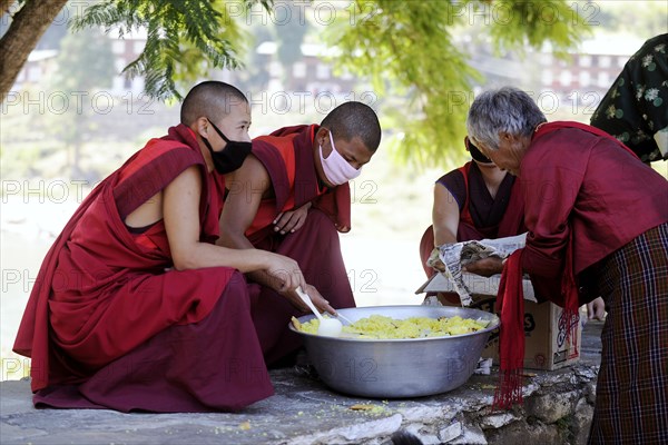 Monks distributing rice to a needy visitor at the entrance of a building in Punakha Dzong fortress