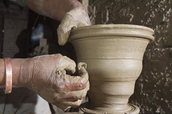 Man making pottery by hand with simple equipment