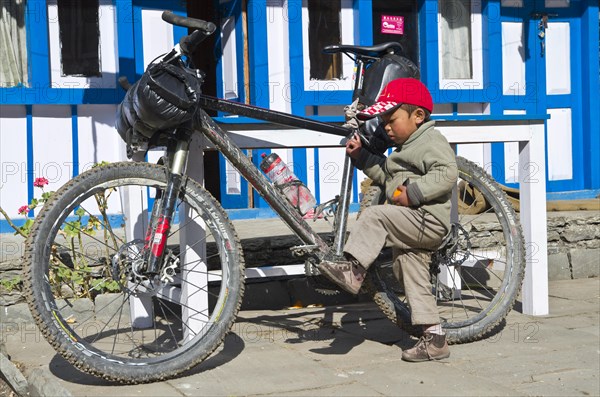 Local boy playing with the mountainbike of a tourist