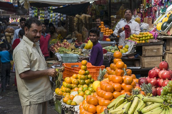 Street vendor arranging oranges for sale at a fruit stall