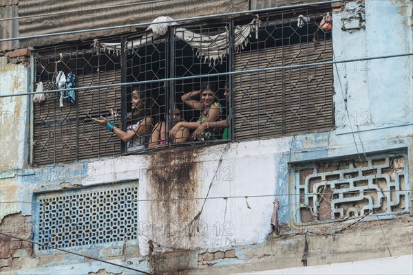 Prostitutes looking out of a window secured with bars waving to potential customers in the redlight district