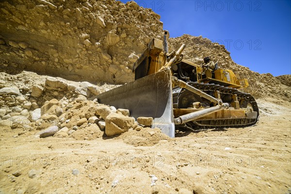 A caterpillar is cleaning the road after a landslide at a road construction site