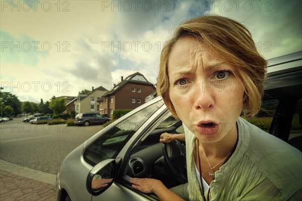 Angry woman car driver sticking out her head out of the window