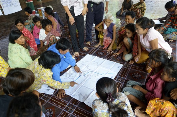 Men and women from the village discussing with representatives of a charity organization