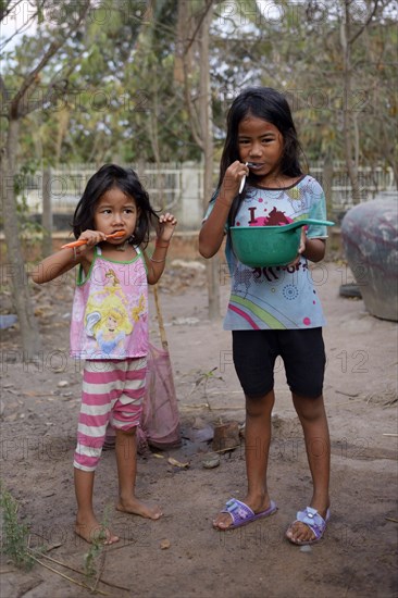 Two girls brushing their teeth outside a house