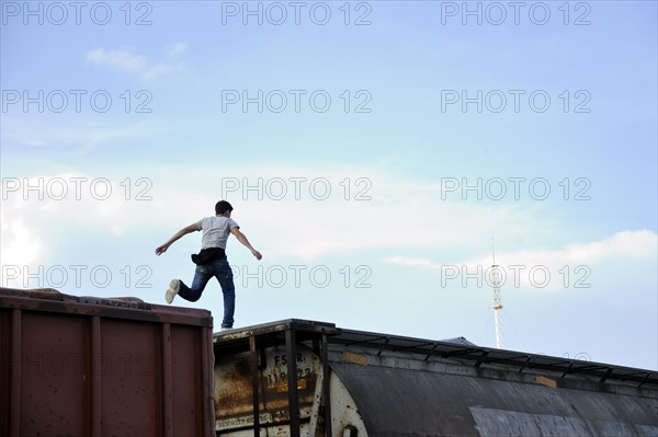 Illegal immigrant from Latin America on his way to the U.S. jumping from one waggon to another trying to reach the U.S. border as a stowaway on freight trains