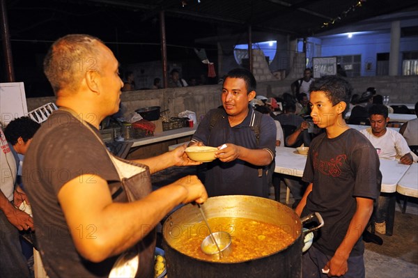 Migrants from Latin America crossing Mexico on their way to the U.S. receiving food in a Christian shelter