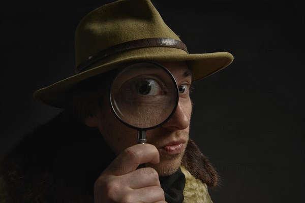Man holding magnifying glass in front of his eye