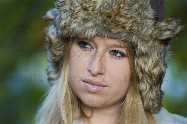 Young woman wearing a fur hat and looking pensive