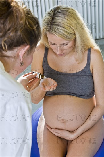 Pregnant woman recieving homeopathic medicine from her midwife during delivery