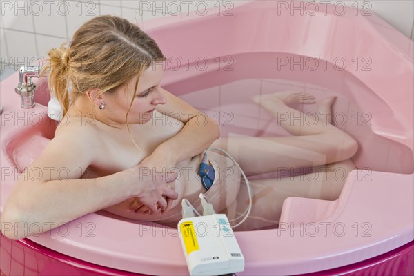 Woman during childbirth with a cardiotocography or CTG in a birthing bath in the maternity delivery room