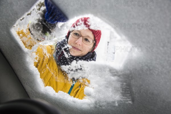 Young woman cleaning a car of ice and snow