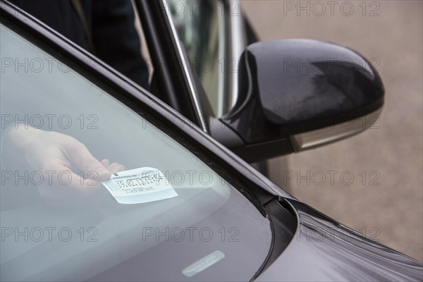 Woman placing a parking ticket in a visible location in her car