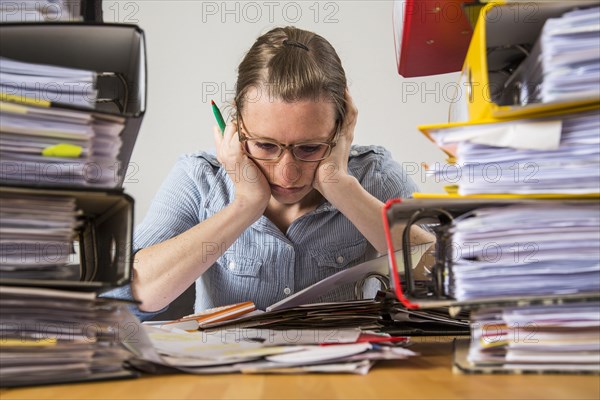 Woman working at a desk between stacks of files