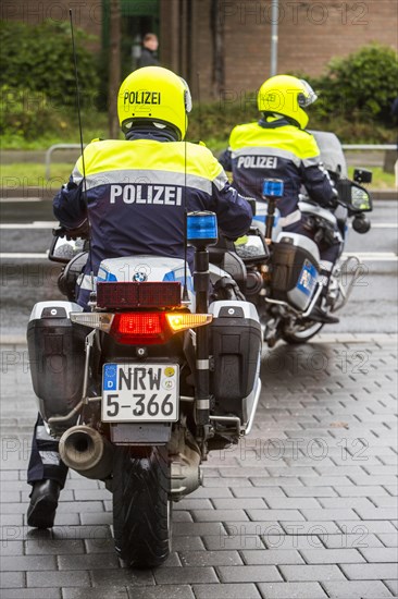 Policemen wearing yellow helmets on motorcycles