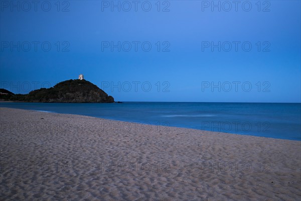 Baia di Chia beach with the Saracen Tower at dusk