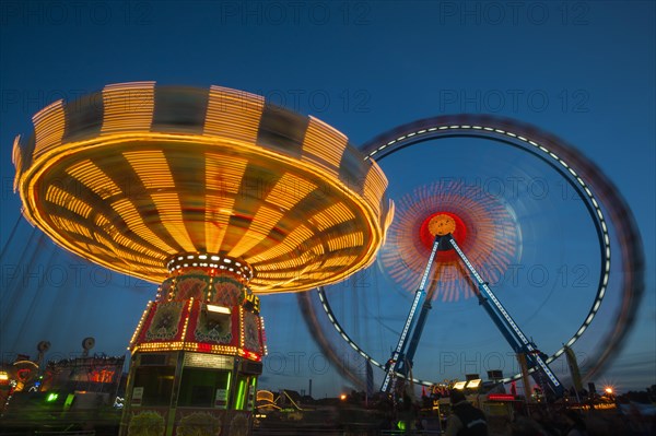 Chair-o-plane or wave swinger and a ferris wheel at dusk