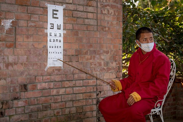 A monk from Amitabha Monastery carrying out a vision test for poor villagers