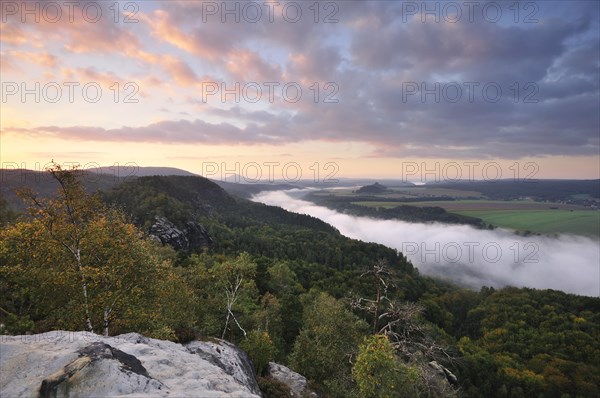 View from the Schrammsteine rocks over the Elbe Valley towards Zirkelstein and Kaiserkrone in autumn at sunrise