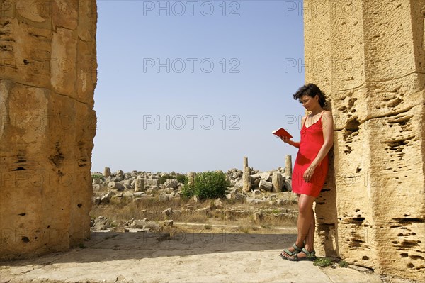 Woman holding a book leaning against a column of Temple E