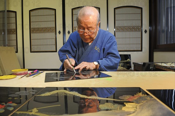 Japanese artisan scraping a bamboo motif onto the top lacquer coat