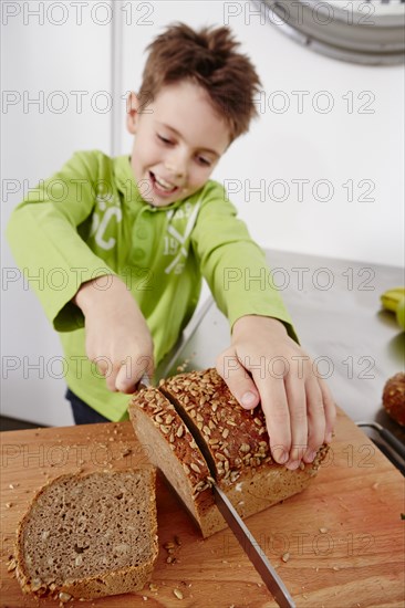 Boy cutting slices off a whole wheat bread