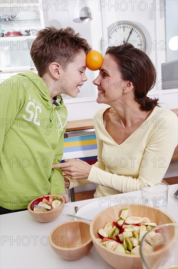 Mother and son playing at home with an orange