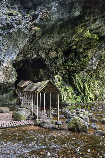 Covered wooden bridge leads into the partly flooded Smoo Cave limestone cave