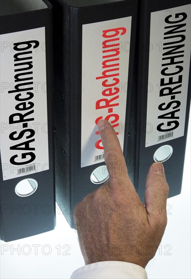Hand pointing to a ring binder labeled Gasrechnung