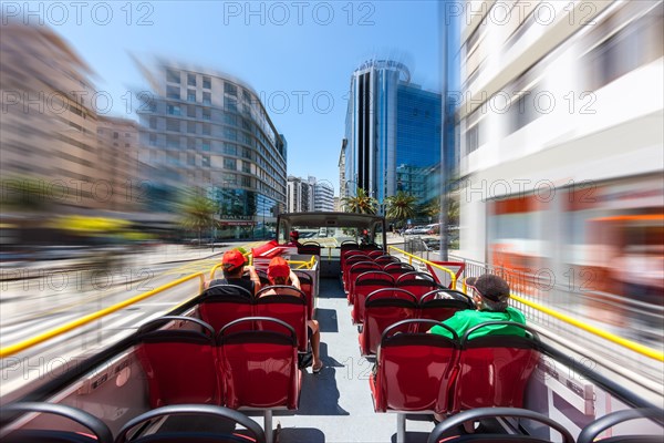 Tourist bus traveling past modern office buildings on Av. de Salle