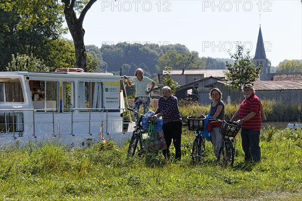 Holidaymakers in front of a house boat on the Canal des Vosges