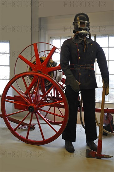 Firefighter wearing a breathing protection mask in front of a hose reel