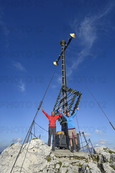 Hikers at the summit cross on the summit of Kampenwand Mountain